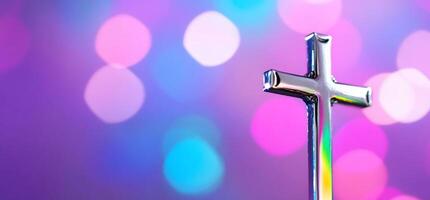 A shiny cross against a colorful bokeh background. photo