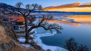 Stunning Sunset Over Frozen Lake with Mountain View and Lakeside House photo
