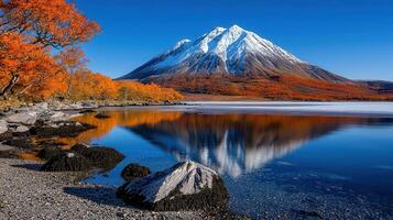Stunning Autumn Landscape Snow capped Mountain Reflected in Calm Lake with Colorful Trees photo