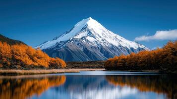 Majestic Snow Capped Mountain Peak Reflected in Calm Autumn Lake Scenic Landscape Photography photo