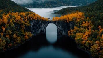 Autumnal Landscape Stone Arch Bridge over Misty Lake Surrounded by Colorful Fall Foliage photo