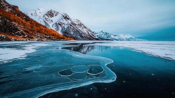 Stunning Winter Landscape Frozen Lake with Ice Bubbles Mountains and Autumnal Foliage photo