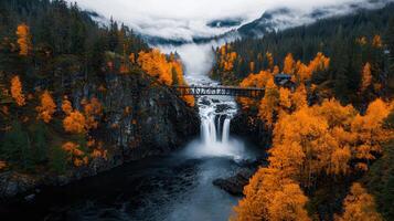 Majestic Waterfall Cascading Through Autumnal Forest Bridge and Misty Mountains photo