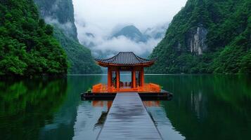 Serene Pavilion on Calm Lake Surrounded by Lush Green Mountains and Misty Peaks photo