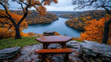 Scenic Autumnal Lake View from a Rustic Wooden Picnic Table Overlooking Colorful Fall Foliage photo