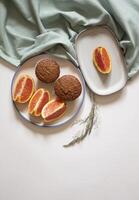 Chocolate cupcakes in a plate with sliced oranges on a white background flat lay photo
