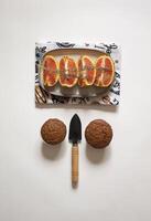 Chocolate cupcakes in a plate with sliced oranges and a small shovel on a white background flat lay photo