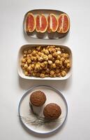 Cupcakes in a plate with sliced oranges and caramel popcorn on a white background flat lay photo