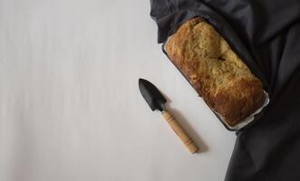 Banana bread next to a small shovel on a white background photo