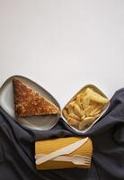 Fruit pastry slice on a plate with a plate of French fries and a fork and knife. photo