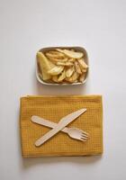 French fries on a plate next to a fork and a knife on a white background photo