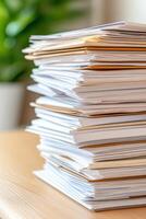 Stack of organized documents on a wooden table with soft focus background of greenery photo