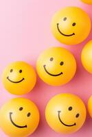 Creative arrangement of small yellow smiley face balls in a spherical shape on a minimalistic background with soft lighting for a playful artistic theme photo