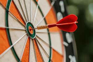 Orange and white dartboard showcasing a red dart hitting the bullseye, illustrating precision and achievement in a competitive game photo