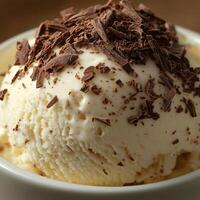 A close-up of vanilla ice cream in a white bowl, topped with large chocolate chunks. The rich and creamy texture contrasts with the deep brown chocolate pieces photo