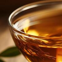 A glass cup filled with warm amber tea, with delicate tea leaves floating inside. The rich color, gentle reflections, and herbal infusion create a calming and aromatic tea experience photo