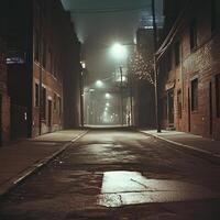 A foggy night alley with wet pavement reflecting the glow of distant streetlights. Tall buildings form a narrow passage, while scattered cables and poles add to the urban scenes depth photo