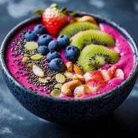 Smoothie bowl with dragon fruit puree, topped with kiwi, banana, strawberries, blueberries, almonds, oats, and chia seeds nutritious meal in dark bowl on a textured background, ideal for healthy diet photo