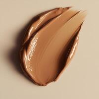 Chocolate-toned foundation smear with soft, blendable texture and subtle radiance fluid consistency creates seamless, skin-like finish, with natural highlights reflecting light on the creamy surface photo
