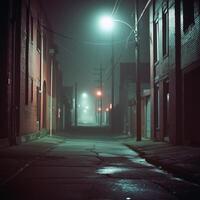 A silent alleyway at night, surrounded by tall brick buildings. Faint streetlights cast dim reflections on the uneven pavement. The mist softens the distant glow, creating a sense of emptiness photo