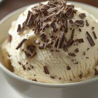 A close-up of vanilla ice cream in a white bowl, drizzled with melted chocolate and sprinkled with small chocolate flakes. The smooth, creamy texture is complemented by the rich chocolate layers photo
