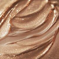 A luminous, shimmering bronzer swatch with a silky, metallic finish. The reflective particles create a radiant effect, emphasizing the smooth, creamy texture of the makeup formula photo