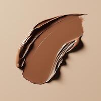 A rich, creamy brown foundation swatch with smooth, even texture on a neutral beige background. The thick application and natural sheen highlight the formulas blendability and coverage photo