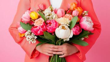 Beautiful bouquet of vibrant tulips and peonies held against a soft pink background during springtime celebration photo