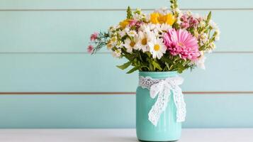Brightly colored flowers arranged in a mason jar on a white table with a soft blue wall backdrop photo