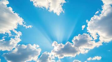 Bright blue sky with fluffy clouds and radiant sunlight breaking through during midday hours photo