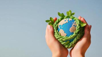 Holding a small globe surrounded by green vines and leaves in a clear blue sky during a bright day photo