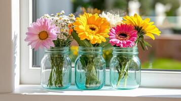 Bright wildflowers in vintage jars arranged beautifully on a sunny windowsill photo