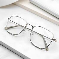 A pair of simple silver-framed reading glasses with clear lenses, displayed on a clean white background photo