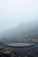 A circular platform on a rocky hill with sparse vegetation, shrouded in thick fog, creating a mysterious and ethereal atmosphere photo