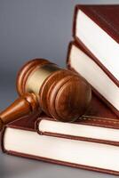 Brown wooden gavel with stack of books on gray table photo