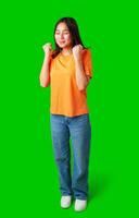 Joyful woman celebrates success in casual outfit against a vibrant green background in a studio setting photo