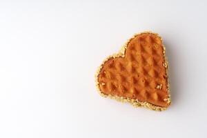 Heart-shaped waffle crafted from golden batter adorned with a crispy texture showcased against a white background photo