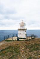 Lighthouse overlooking a calm ocean under a cloudy sky during the day near a coastal area photo