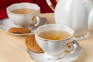 White porcelain cup of tea and oat cookies on a table photo