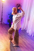 Confident dancer showcasing moves in a brightly lit studio during an evening practice session photo