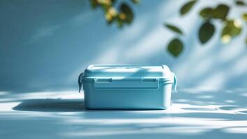 Light blue storage container placed on a table with soft shadows and leafy sunlight on a calm afternoon photo