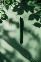 Green pen resting on a muted surface surrounded by soft shadows of leaves creating an inviting workspace atmosphere photo