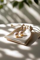 Elegant pearl earrings resting on a stylish pouch with soft shadows and natural light filtering through leaves photo