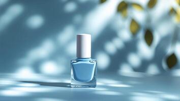 Unique blue nail polish bottle positioned on a softly lit surface with shadows and leaves in the background photo