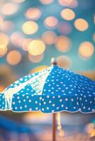 Bright blue polka dot umbrella stands under warm sunlight with bokeh background creating a dreamy atmosphere during a summer day photo