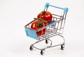 Small cart with fresh red tomatoes on a white background photo