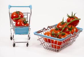 Miniature shopping carts filled with fresh red tomatoes on display photo