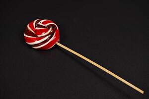 Colorful spiral lollipop on a stick against a dark background photo