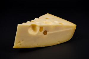 Cheese wedge with holes displayed on a black background photo