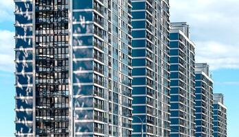Modern high-rise building in downtown metropolis. Glass facade with views of blue sky and clouds, photo